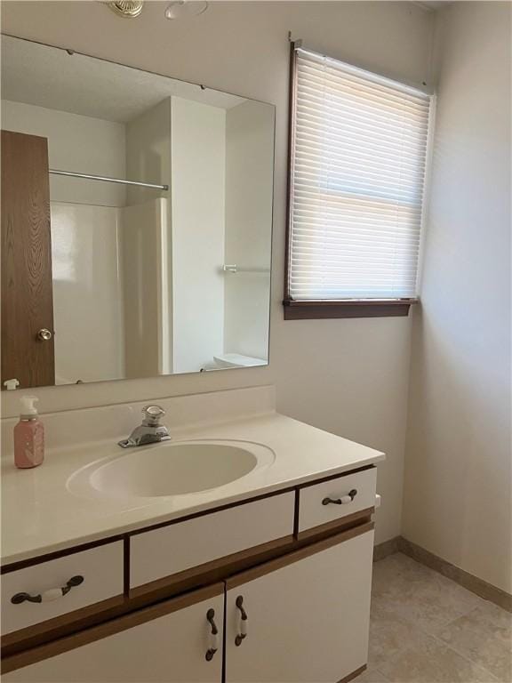 bathroom with tile patterned flooring, a shower, and vanity