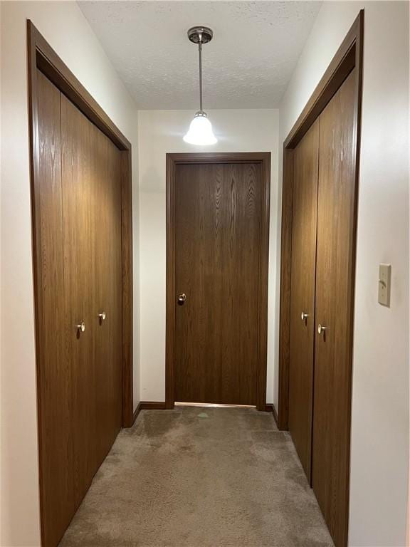 hall featuring dark carpet and a textured ceiling