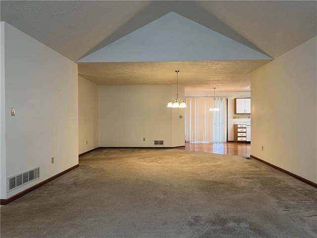 carpeted spare room with vaulted ceiling, a textured ceiling, and a chandelier