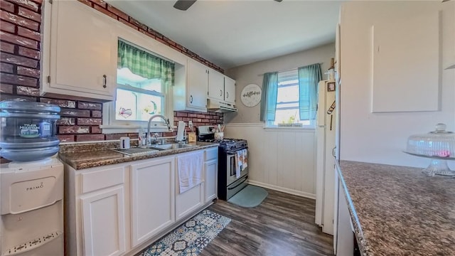 kitchen featuring dark wood-type flooring, stainless steel gas stove, white cabinets, and a healthy amount of sunlight