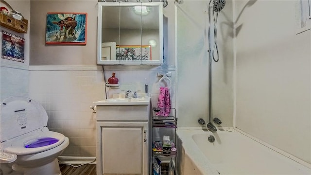 full bathroom with tile walls, wood-type flooring, toilet, vanity, and shower / bathtub combination