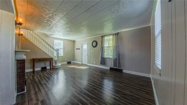 unfurnished living room with dark hardwood / wood-style floors and wooden walls