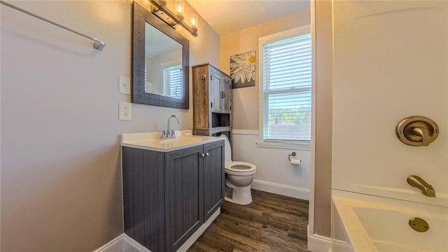 bathroom featuring a washtub, vanity, wood-type flooring, and toilet