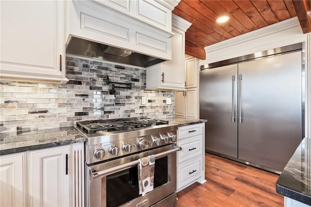 kitchen featuring wood ceiling, high quality appliances, dark stone countertops, white cabinets, and light hardwood / wood-style floors