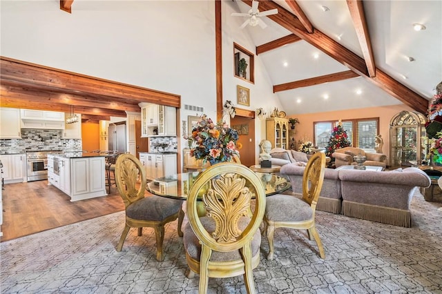 dining area with beam ceiling, high vaulted ceiling, light hardwood / wood-style flooring, and ceiling fan