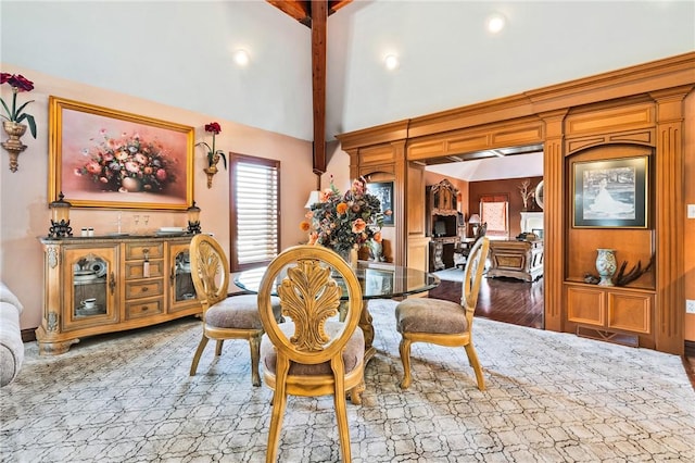 dining room with beam ceiling, light wood-type flooring, and high vaulted ceiling