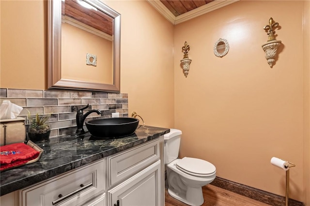 bathroom with decorative backsplash, ornamental molding, vanity, hardwood / wood-style flooring, and toilet