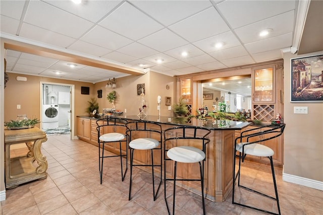 bar with light tile patterned floors, washer / clothes dryer, and a drop ceiling