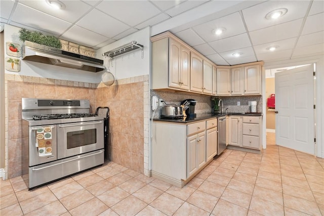 kitchen featuring appliances with stainless steel finishes, a paneled ceiling, light tile patterned floors, and range hood