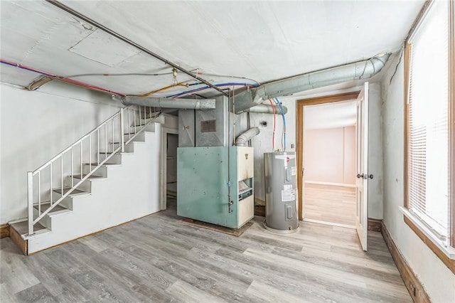 basement featuring heating unit, electric water heater, and hardwood / wood-style floors