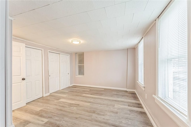 unfurnished bedroom featuring light hardwood / wood-style floors and multiple closets