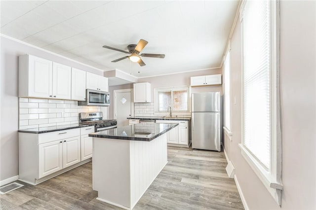 kitchen featuring a kitchen island, white cabinetry, stainless steel appliances, and a wealth of natural light