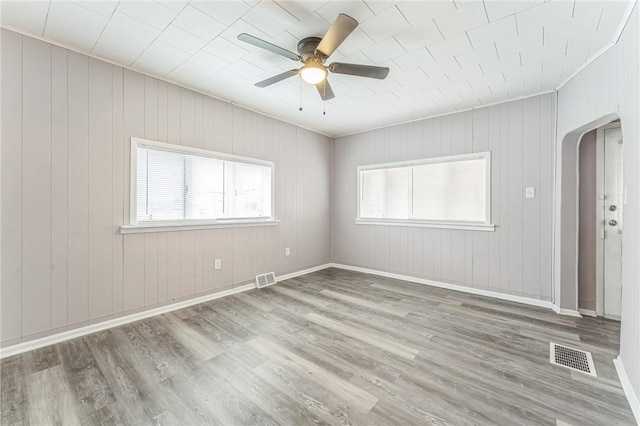 spare room featuring wooden walls, ceiling fan, and light hardwood / wood-style floors