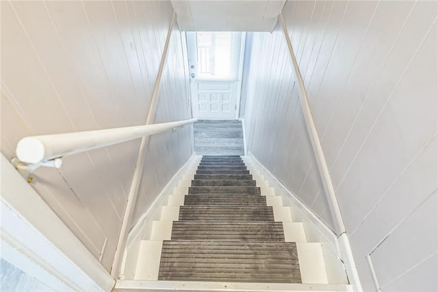 staircase with wood walls and wood-type flooring