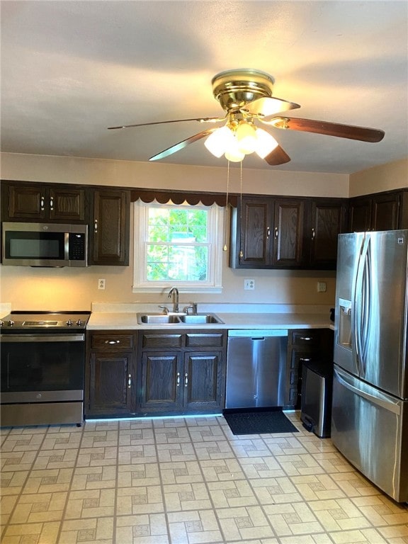kitchen with a ceiling fan, appliances with stainless steel finishes, dark brown cabinets, a sink, and light countertops