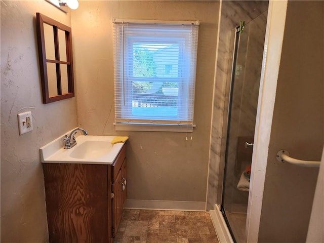 bathroom with stone finish floor, a stall shower, vanity, and baseboards