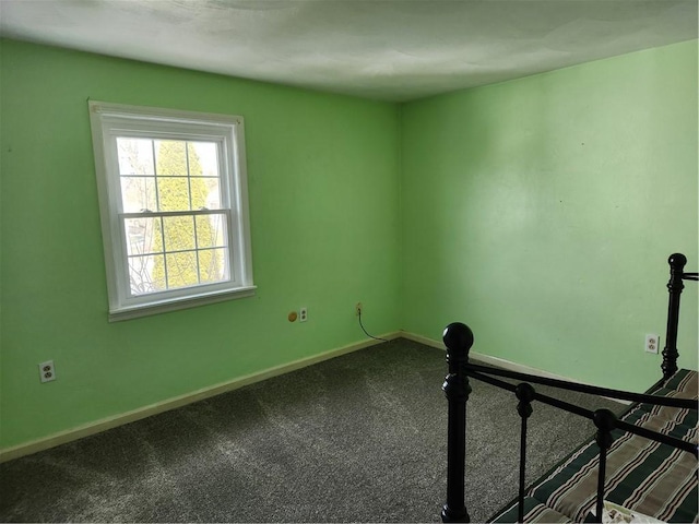 unfurnished room featuring dark carpet and baseboards