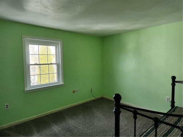 empty room featuring dark carpet and baseboards