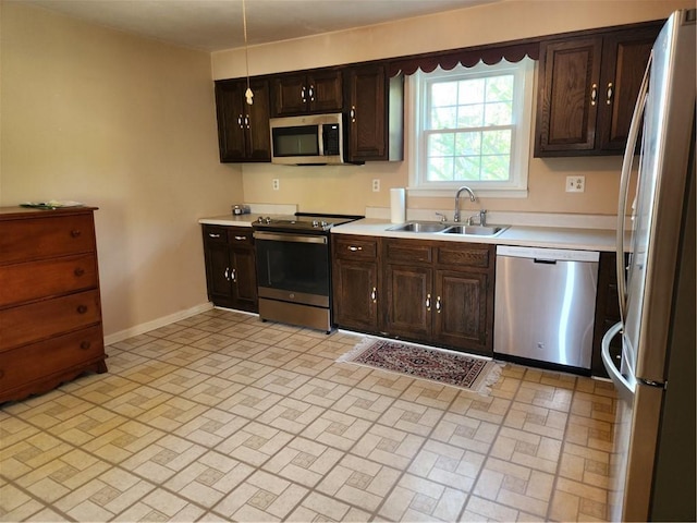 kitchen with light countertops, appliances with stainless steel finishes, brick patterned floor, and a sink