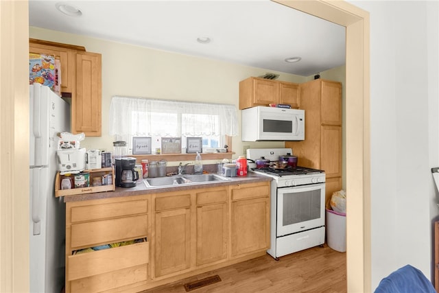 kitchen with light brown cabinets, white appliances, light hardwood / wood-style flooring, and sink