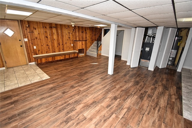 basement with dark hardwood / wood-style flooring, gas water heater, a drop ceiling, and wooden walls