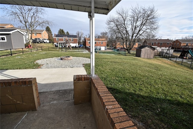 view of yard with a fire pit, a storage unit, and a patio area