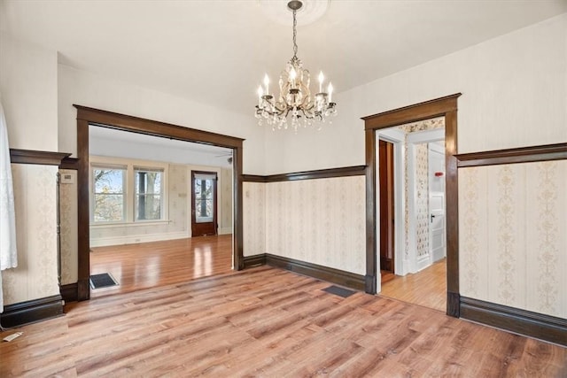 unfurnished dining area featuring wood-type flooring and a notable chandelier