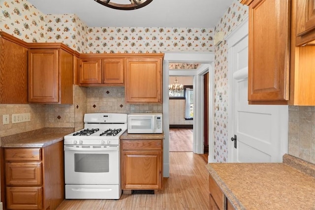 2035 Biggs Ave, Fineview, PA 15214 - kitchen featuring white appliances, wallpapered walls, a chandelier, light wood finished floors, and brown cabinetry