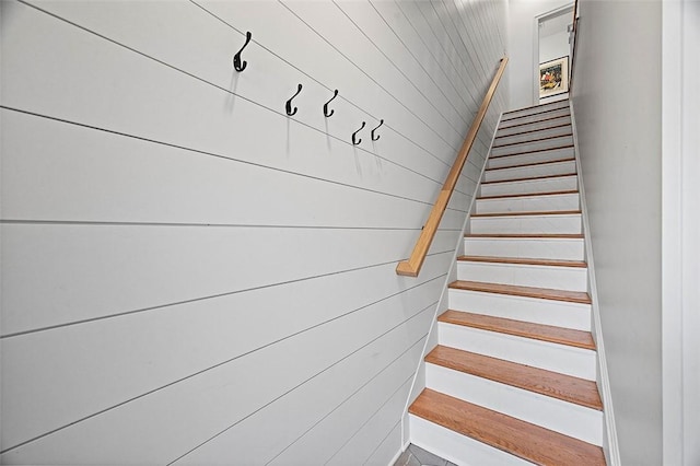 stairway featuring wooden walls