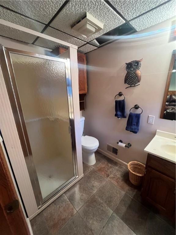 bathroom featuring a paneled ceiling, toilet, an enclosed shower, and vanity