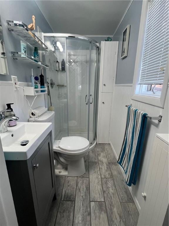 bathroom with hardwood / wood-style floors, vanity, toilet, and a shower with door