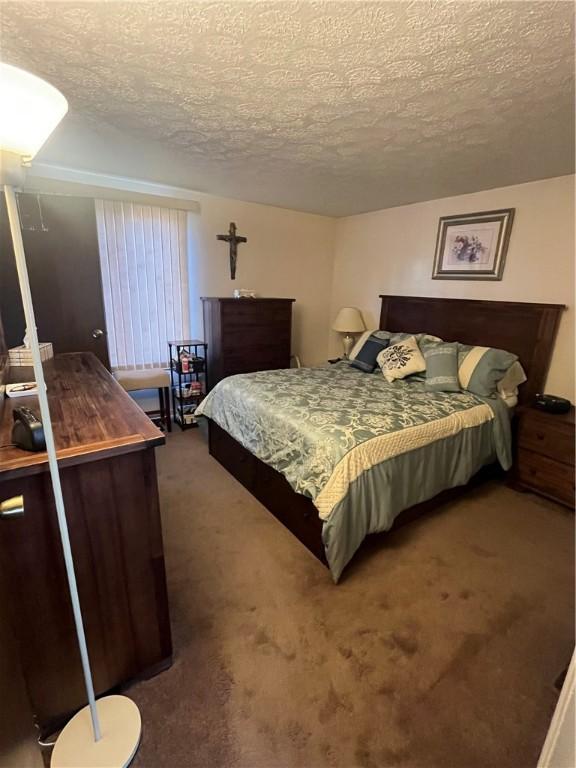 bedroom with dark carpet and a textured ceiling