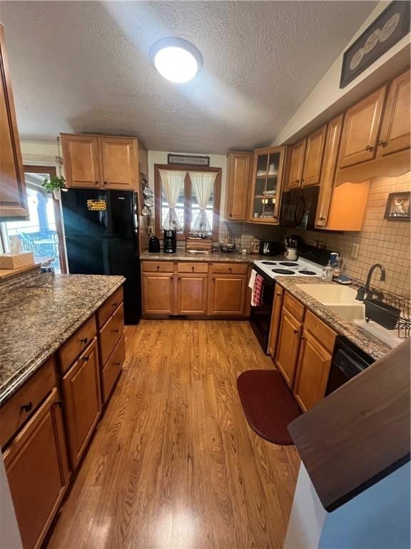 kitchen with black appliances, light wood-type flooring, a textured ceiling, and tasteful backsplash