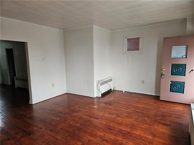 empty room featuring dark hardwood / wood-style floors and radiator