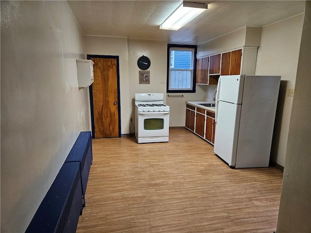 kitchen with a textured ceiling, light wood-type flooring, white appliances, and sink