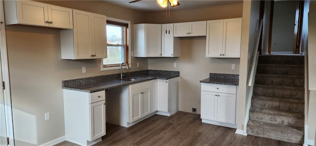 kitchen with dark hardwood / wood-style floors, white cabinetry, dark stone countertops, and sink