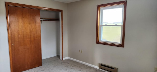 unfurnished bedroom featuring baseboard heating, light carpet, and a closet