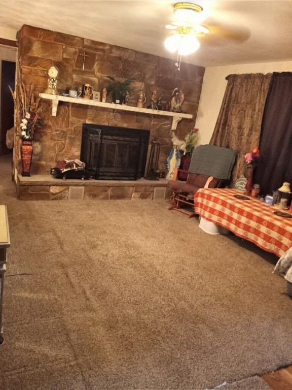 carpeted living room with ceiling fan and a fireplace