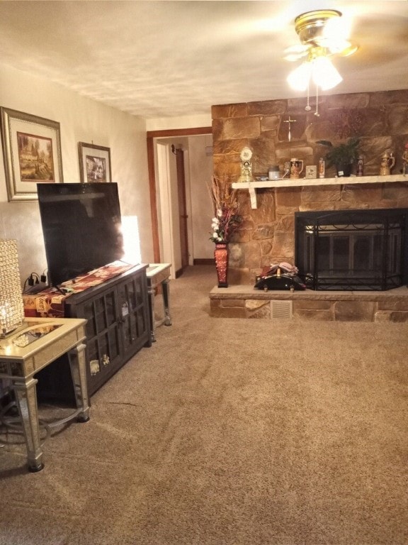 living room with carpet flooring, ceiling fan, and a stone fireplace