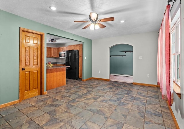 kitchen featuring kitchen peninsula, a textured ceiling, black fridge, and ceiling fan