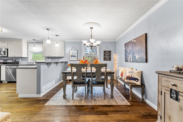 dining area with dark hardwood / wood-style flooring, ornamental molding, a textured ceiling, and a notable chandelier