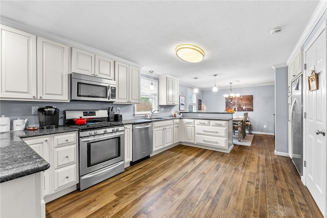 kitchen with white cabinetry, dark hardwood / wood-style flooring, kitchen peninsula, pendant lighting, and appliances with stainless steel finishes