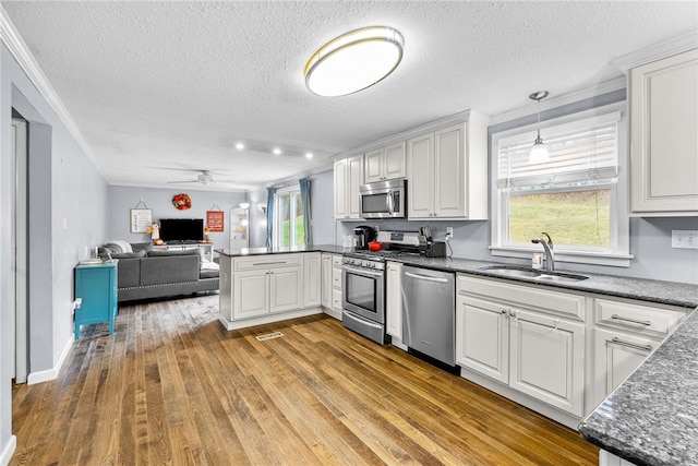 kitchen with sink, stainless steel appliances, light hardwood / wood-style flooring, a textured ceiling, and white cabinets