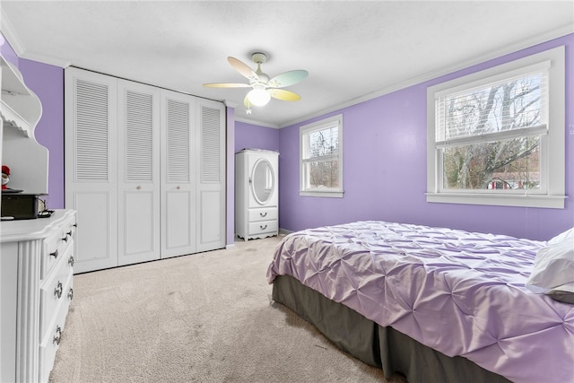 bedroom with a closet, light colored carpet, ceiling fan, and ornamental molding