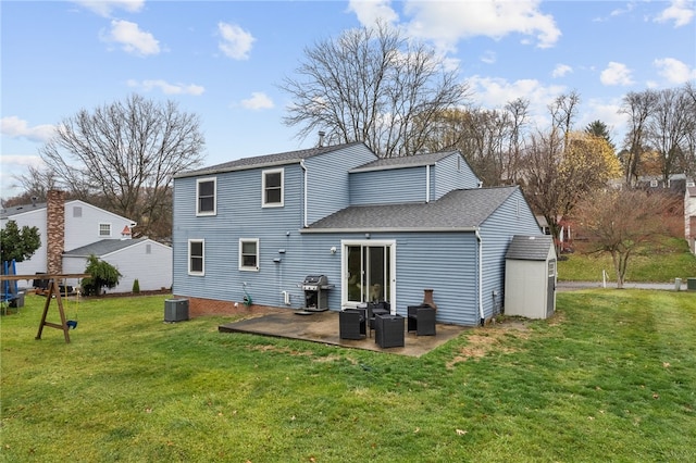 rear view of property with a lawn, central AC, a patio, and a storage shed