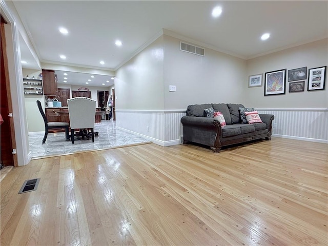 living room featuring light wood-type flooring and crown molding