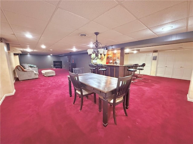 carpeted dining room featuring bar area and a paneled ceiling