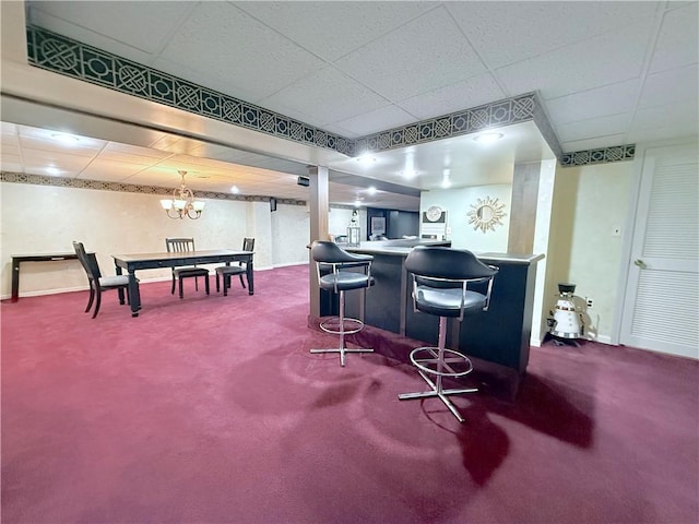 bar with carpet, an inviting chandelier, and a drop ceiling