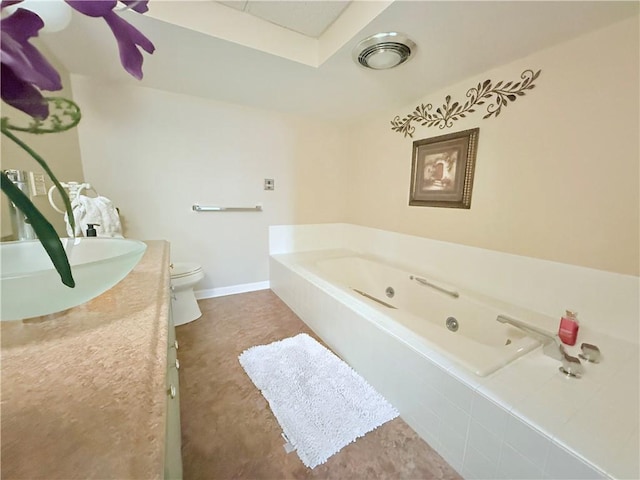 bathroom featuring vanity, a relaxing tiled tub, and toilet