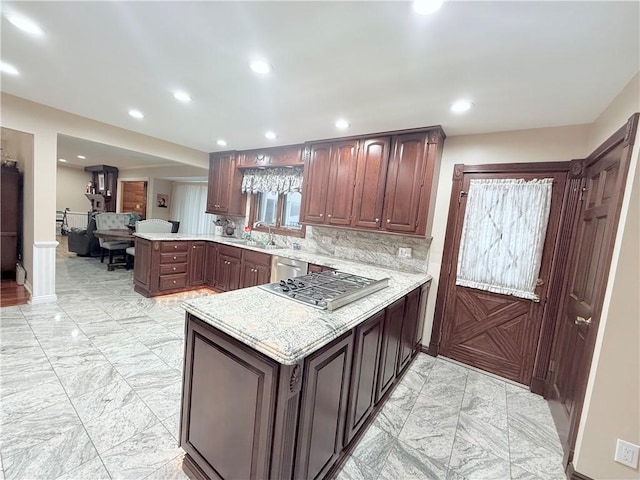 kitchen with sink, appliances with stainless steel finishes, tasteful backsplash, light stone counters, and kitchen peninsula